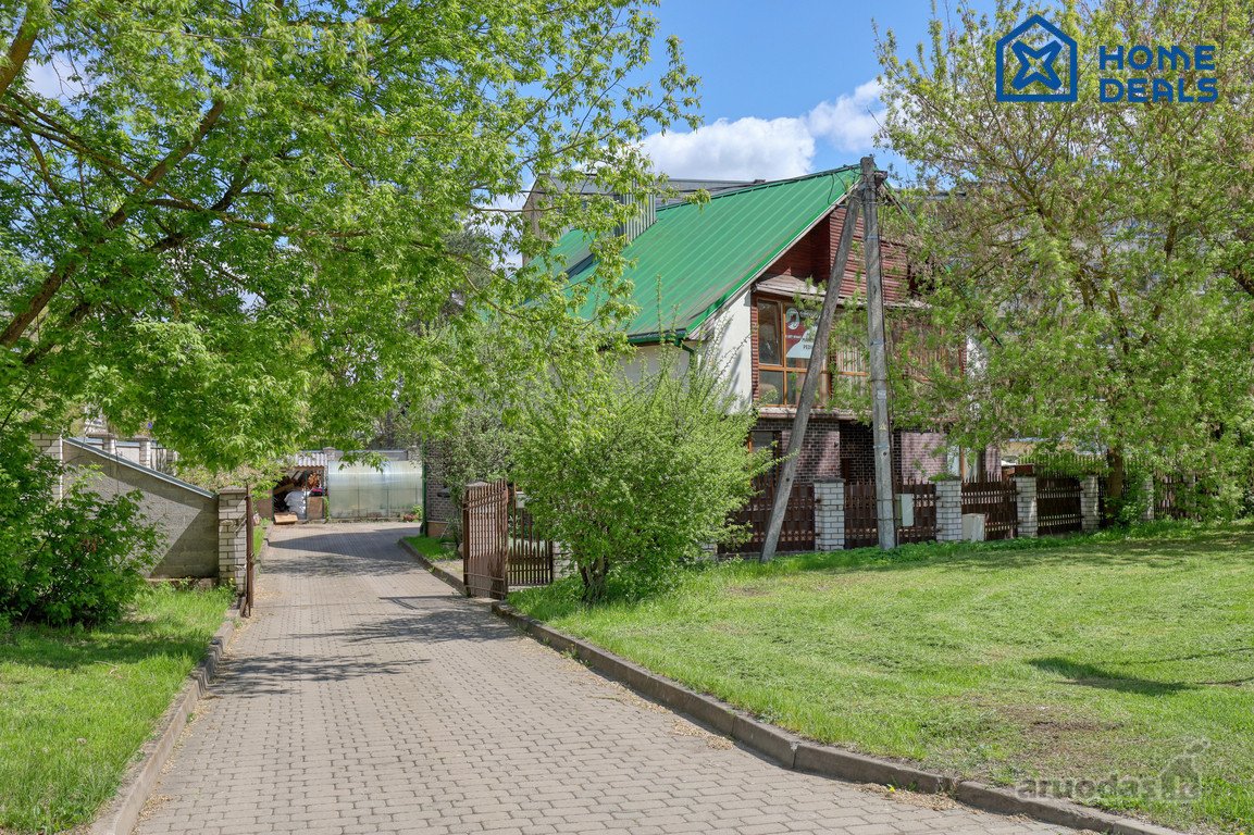 Didelis, trijų aukštų namas apsuptas pušynų